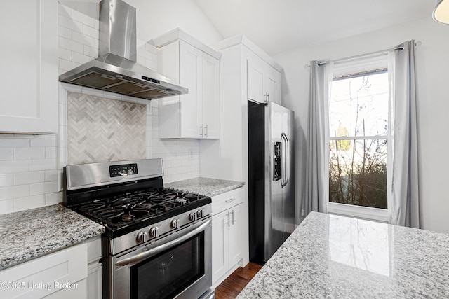 kitchen with light stone counters, white cabinets, stainless steel appliances, and wall chimney range hood