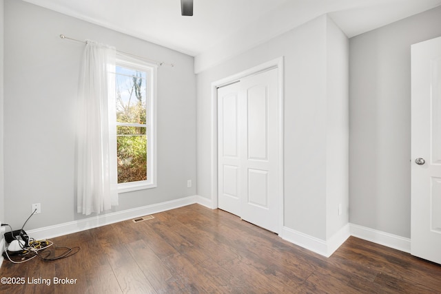 unfurnished bedroom with ceiling fan and dark hardwood / wood-style flooring