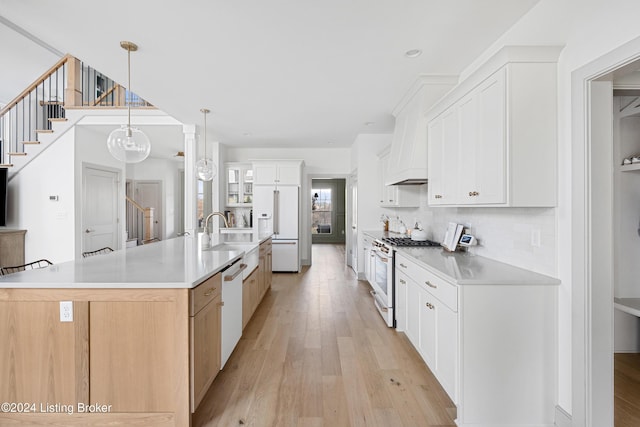 kitchen featuring light wood-type flooring, a spacious island, high quality appliances, white cabinets, and hanging light fixtures