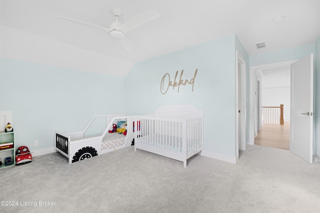 bedroom featuring ceiling fan, light colored carpet, and a nursery area