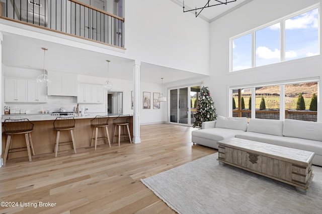 living room with light hardwood / wood-style flooring, an inviting chandelier, a high ceiling, and ornamental molding