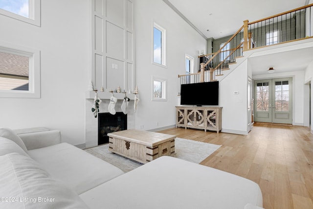 living room featuring french doors, a high ceiling, and light hardwood / wood-style flooring