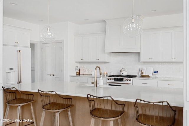 kitchen with white cabinets, a kitchen breakfast bar, decorative light fixtures, and a kitchen island with sink