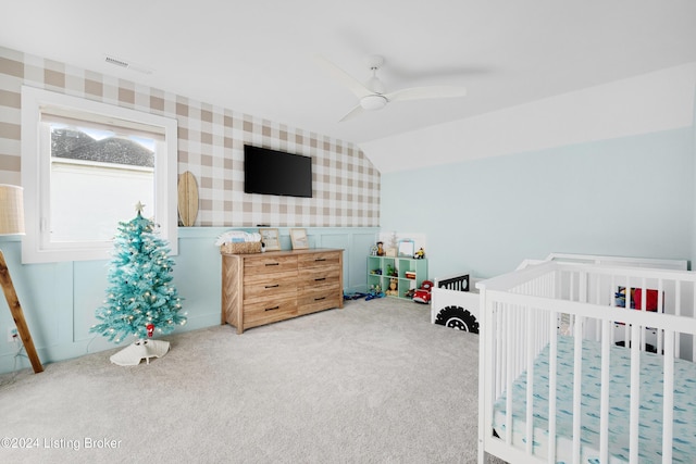 bedroom featuring carpet flooring, ceiling fan, vaulted ceiling, and a nursery area