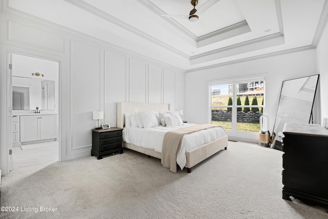 bedroom featuring a raised ceiling, ceiling fan, ornamental molding, connected bathroom, and light colored carpet