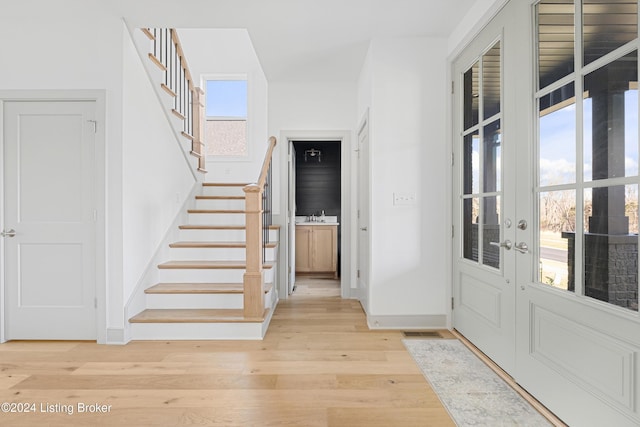 foyer featuring a healthy amount of sunlight, light hardwood / wood-style floors, sink, and french doors