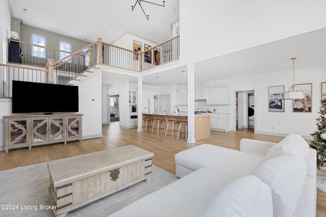 living room featuring a towering ceiling, light wood-type flooring, and a healthy amount of sunlight