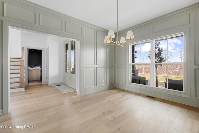 unfurnished dining area featuring a chandelier and light hardwood / wood-style floors