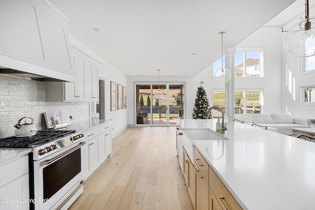 kitchen featuring white cabinetry, light hardwood / wood-style flooring, high end stove, decorative light fixtures, and decorative backsplash