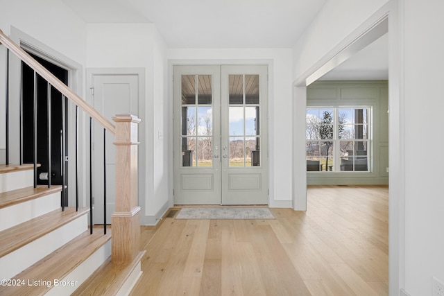 entrance foyer with a healthy amount of sunlight, light hardwood / wood-style floors, and french doors