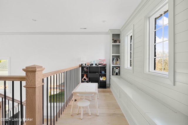 corridor featuring light hardwood / wood-style floors, a wealth of natural light, and ornamental molding