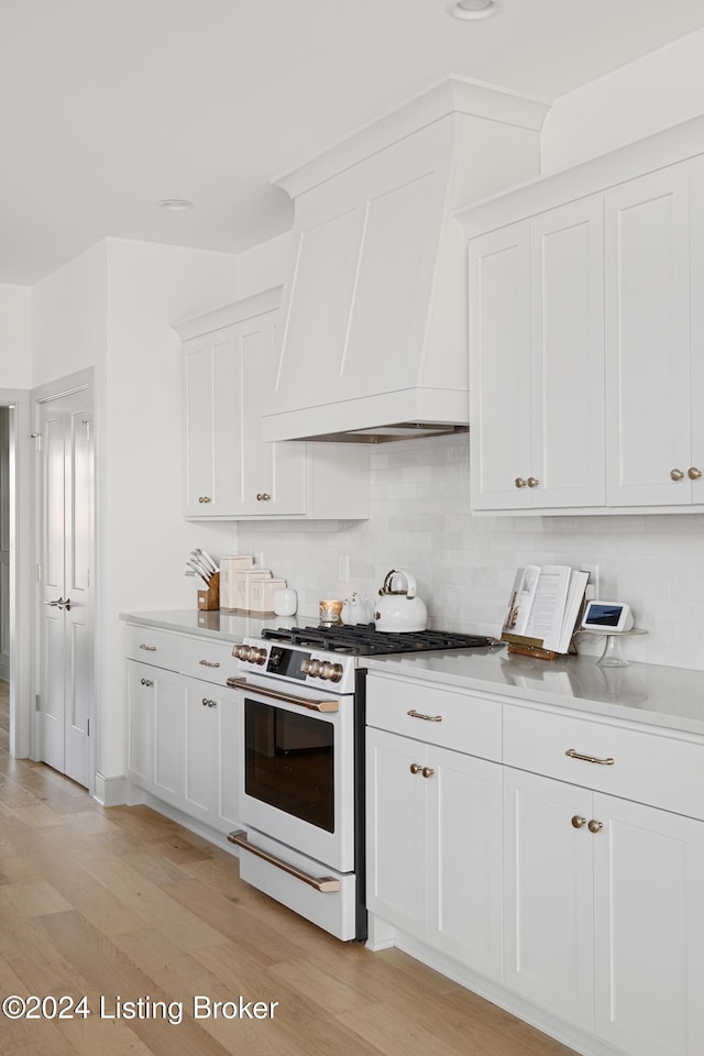 kitchen featuring high end range, light hardwood / wood-style floors, and white cabinets