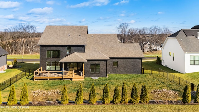 rear view of house featuring a deck and a lawn