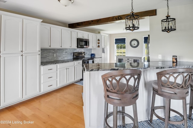 kitchen with pendant lighting, white cabinetry, appliances with stainless steel finishes, and light hardwood / wood-style flooring