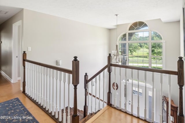 stairway featuring hardwood / wood-style floors, a notable chandelier, and a textured ceiling