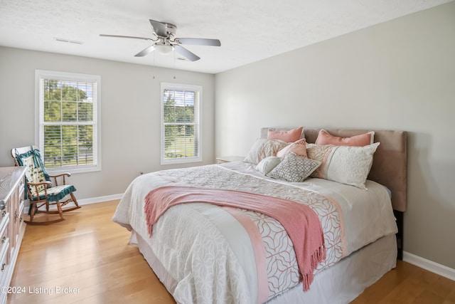 bedroom featuring ceiling fan, light hardwood / wood-style floors, and a textured ceiling