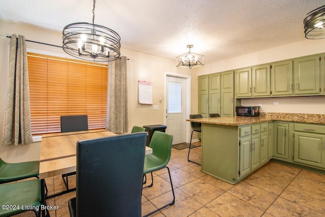 kitchen with a notable chandelier, green cabinets, light stone counters, and hanging light fixtures