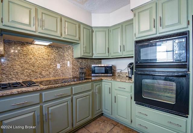 kitchen with green cabinetry, decorative backsplash, a textured ceiling, light tile patterned flooring, and black microwave