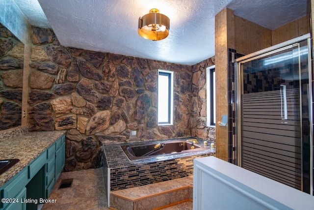 bathroom with vanity, a textured ceiling, and plus walk in shower