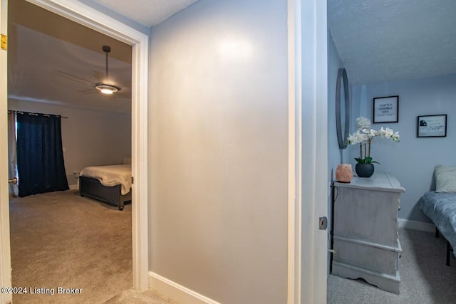 hall featuring a textured ceiling and light colored carpet