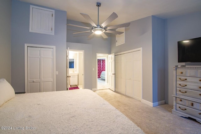 bedroom with multiple closets, ceiling fan, ensuite bathroom, and light carpet