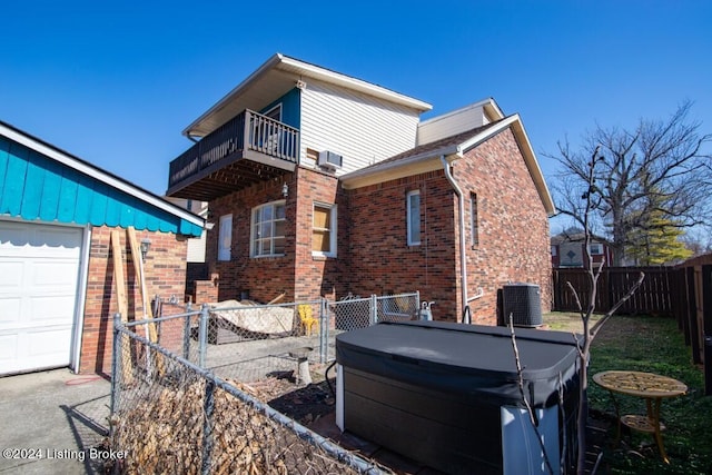 rear view of property with a balcony, a garage, and central AC unit