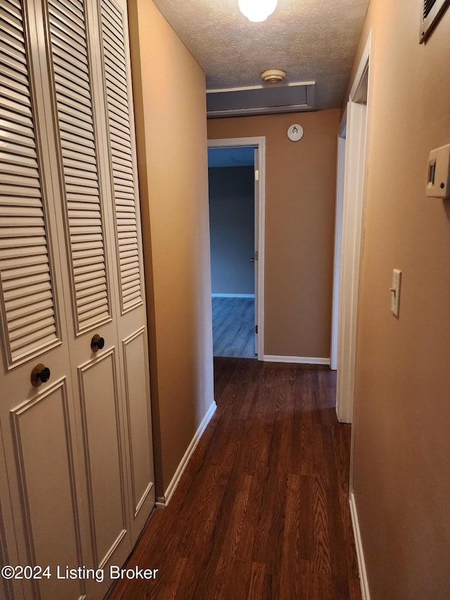 corridor featuring dark hardwood / wood-style flooring and a textured ceiling