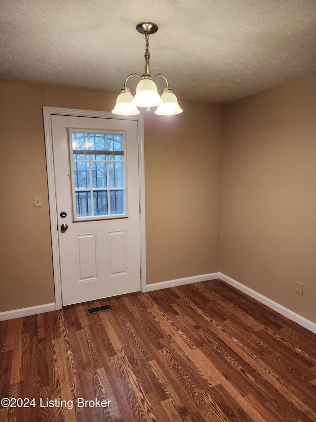 entryway featuring a textured ceiling, a chandelier, and dark hardwood / wood-style floors