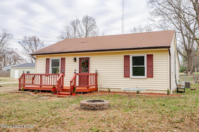 view of front of house with a fire pit, a front yard, a wooden deck, and cooling unit