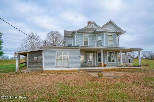 view of front of home featuring a sunroom, covered porch, and a front yard