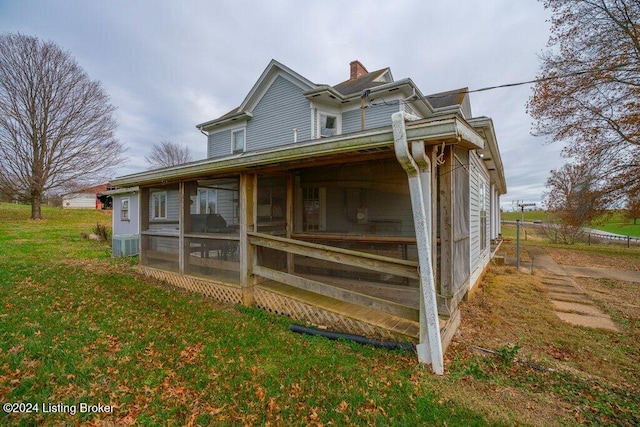 rear view of property featuring a yard and a sunroom