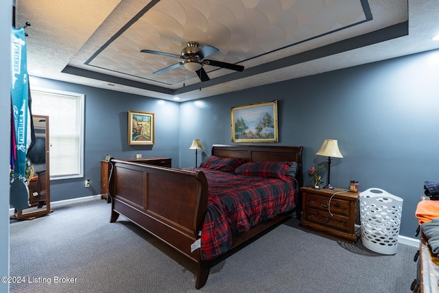 carpeted bedroom featuring ceiling fan and a raised ceiling