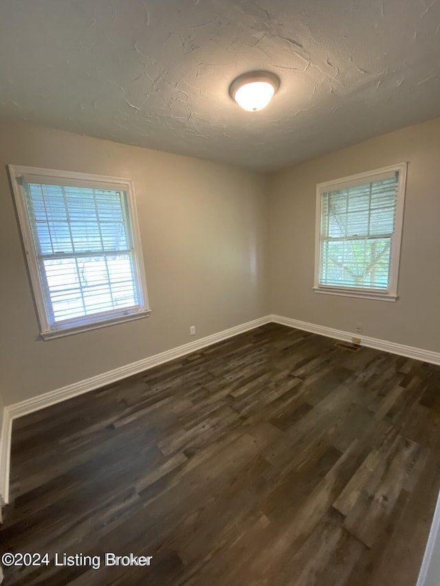 spare room with dark hardwood / wood-style floors and a textured ceiling