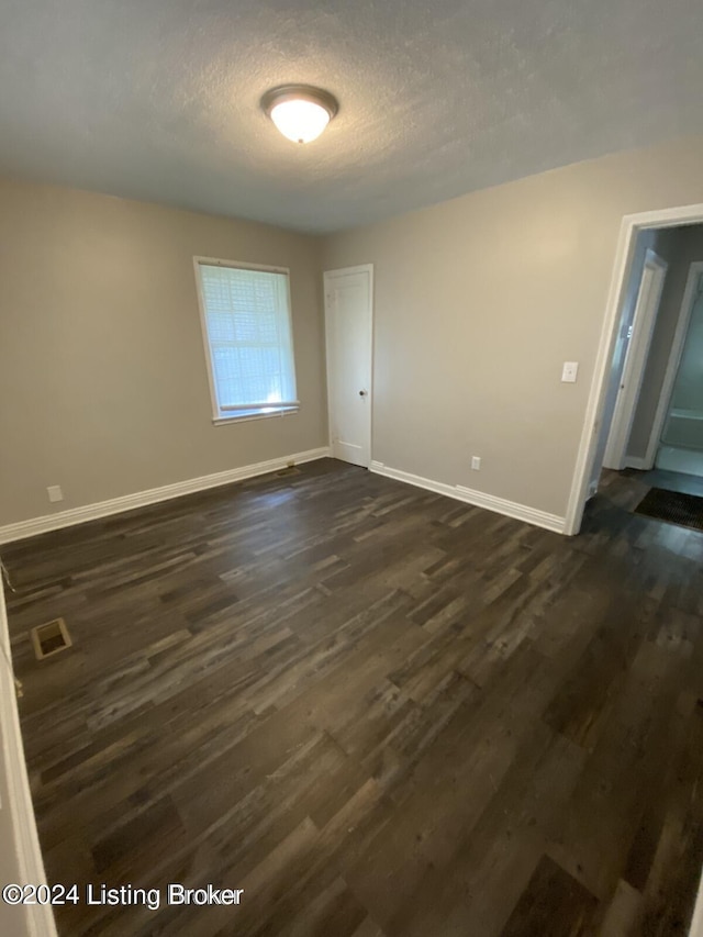 unfurnished room with dark hardwood / wood-style flooring and a textured ceiling