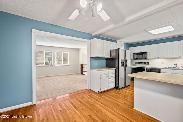 kitchen featuring sink, light hardwood / wood-style flooring, white cabinetry, and black appliances