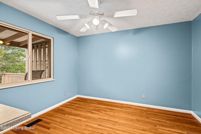 empty room with ceiling fan, a textured ceiling, and hardwood / wood-style flooring