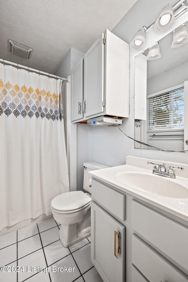 bathroom with tile patterned flooring, vanity, a textured ceiling, and toilet