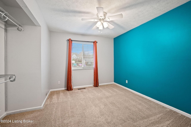 unfurnished room featuring ceiling fan, light carpet, and a textured ceiling