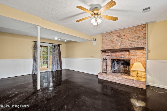 unfurnished living room featuring ceiling fan, a fireplace, concrete flooring, and a textured ceiling