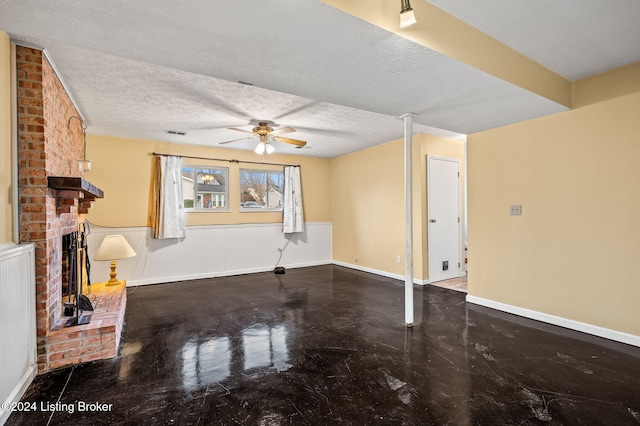 unfurnished living room featuring ceiling fan, a fireplace, concrete flooring, and a textured ceiling