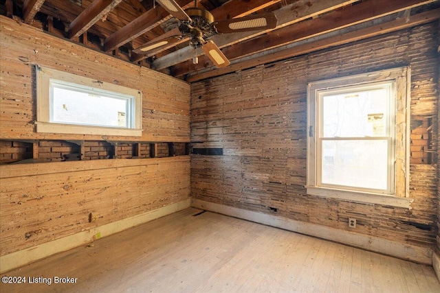 empty room with wooden walls, ceiling fan, and hardwood / wood-style flooring