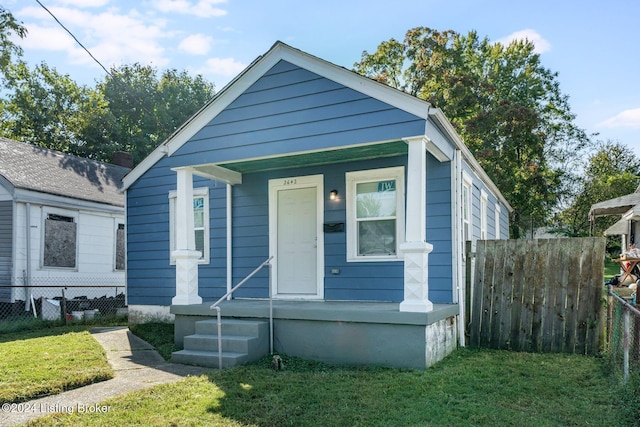 bungalow-style home with covered porch and a front yard