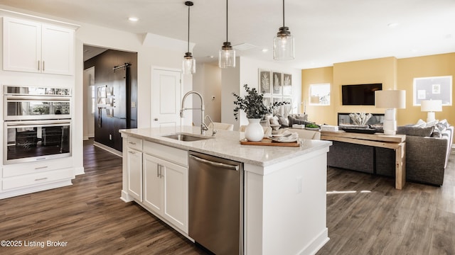 kitchen with appliances with stainless steel finishes, white cabinetry, light stone countertops, and sink