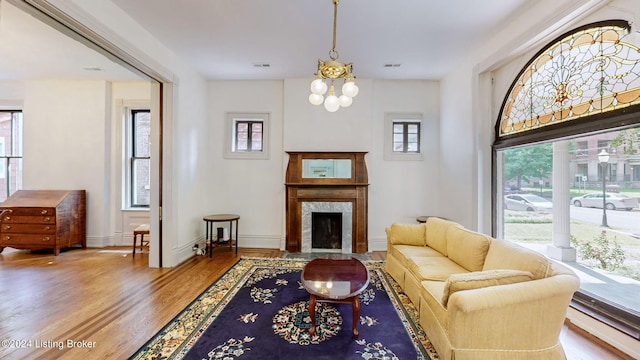 sitting room with a wealth of natural light, hardwood / wood-style floors, a high end fireplace, and a notable chandelier