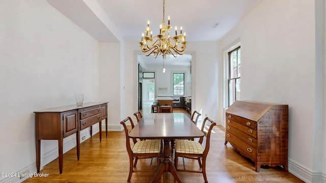 dining room with light hardwood / wood-style flooring and an inviting chandelier