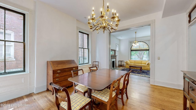 dining area with light wood-type flooring and an inviting chandelier