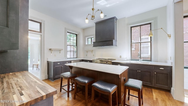 kitchen with stove, light hardwood / wood-style flooring, hanging light fixtures, and custom range hood