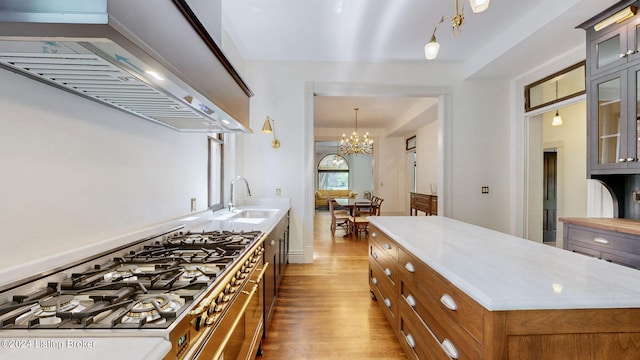 kitchen with pendant lighting, sink, a kitchen island, wood-type flooring, and a chandelier