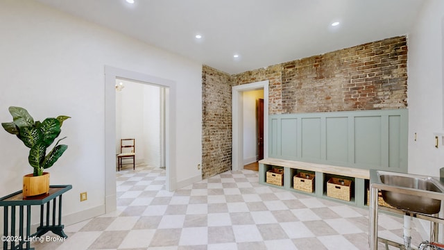 mudroom featuring brick wall