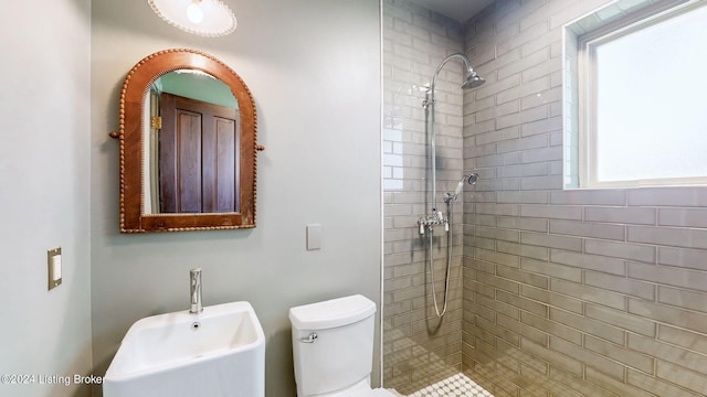 bathroom featuring a tile shower, sink, and toilet